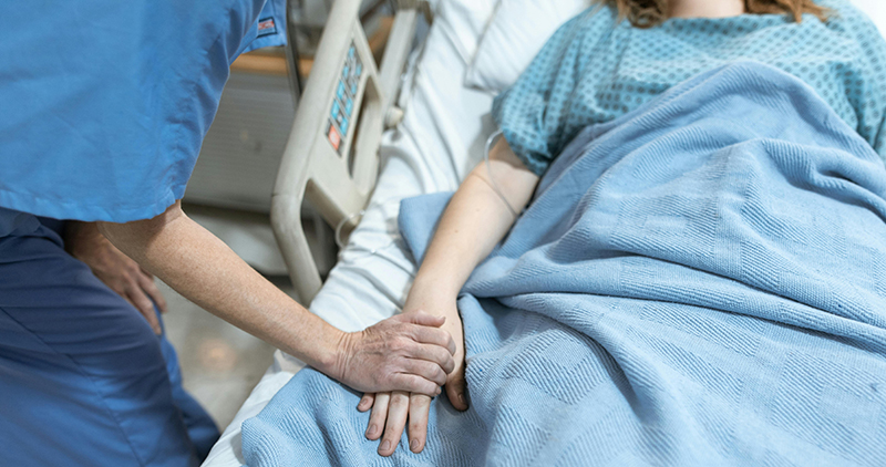 A Nurse holding patients hand.