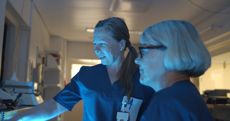 Two nurses standing in clinical situation.
